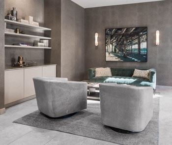 A modern living room with a green couch and grey ottoman.